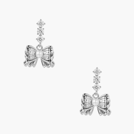 White gold plated drop earrings with three graduated zirconia crystals leading to a bow charm with pearl center