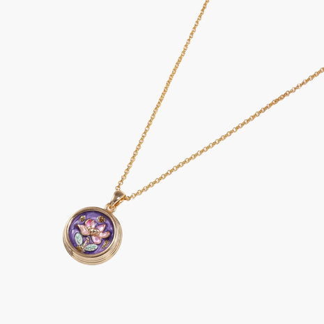 Gold-plated circular pendant with hand-painted purple enamel floral design on delicate chain against cream background