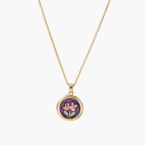 Gold-plated circular pendant with hand-painted purple enamel floral design on delicate chain against cream background