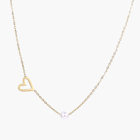Delicate gold necklace with open heart charm and white pearl bead on fine chain against cream background