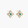 Gold quatrefoil stud earrings with white mother-of-pearl petals and emerald green gemstone center on beige background.