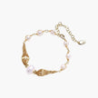Adjustable gold bracelet with freshwater pearls and textured filigree beads on white background, showing clasp detail.