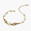 Adjustable gold bracelet with freshwater pearls and textured filigree beads on white background, showing clasp detail.