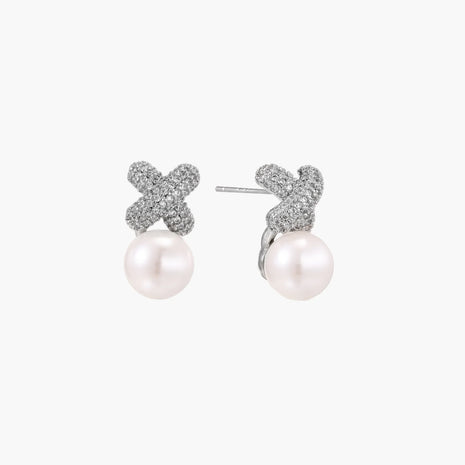 White gold plated studs featuring pavé X-shaped tops with freshwater pearl drops on cream background.