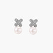 White gold plated studs featuring pavé X-shaped tops with freshwater pearl drops on cream background.