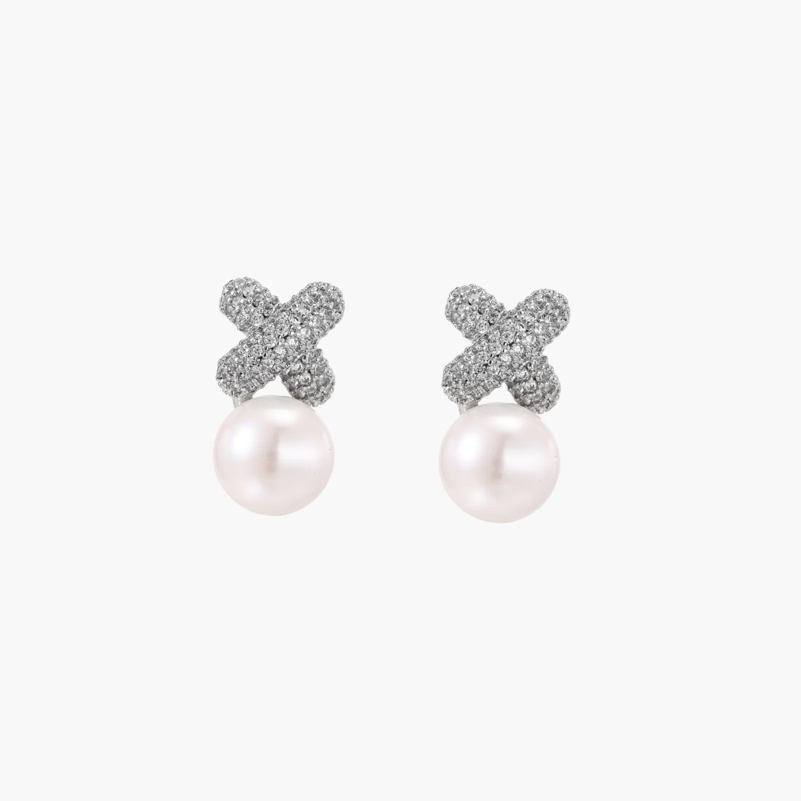 White gold plated studs featuring pavé X-shaped tops with freshwater pearl drops on cream background.