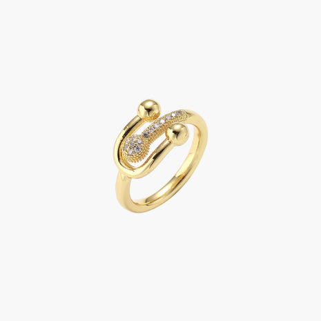 Gold-plated brass ring with safety pin design featuring pavé cubic zirconia stones and dual sphere ends