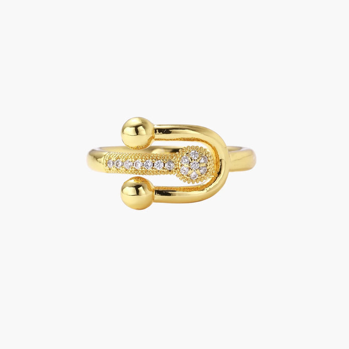 Gold-plated brass ring with safety pin design featuring pavé cubic zirconia stones and dual sphere ends