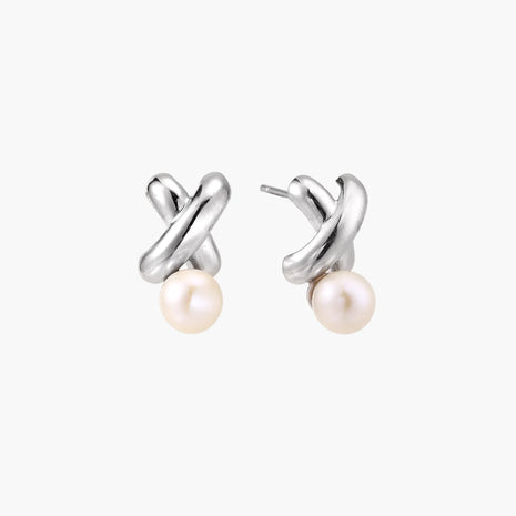 Rhodium-plated silver earrings with twisted X design and freshwater pearl drops on beige background