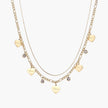 Gold layered necklace set with engraved heart pendants and crystal accents on cream background
