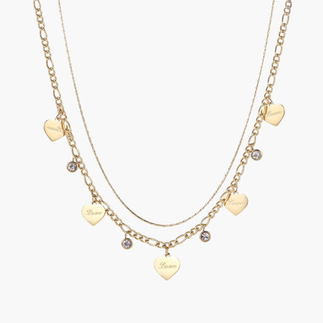 Gold layered necklace set with engraved heart pendants and crystal accents on cream background