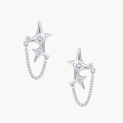 Silver star studs with crescent moon cutouts and zirconia stones connected by delicate chains on white background