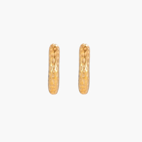Gold-toned hoop earrings with hammered dimpled texture and post closure on cream background