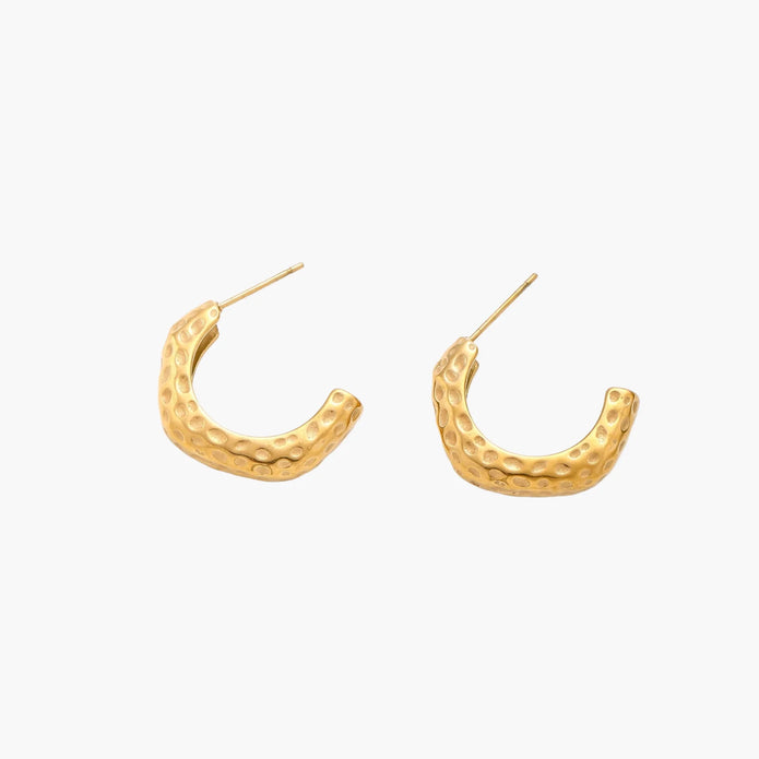 Gold-toned hoop earrings with hammered dimpled texture and post closure on cream background