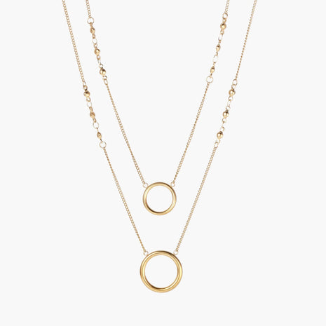 Layered gold necklace set with two open circle pendants and mixed chain styles on beige background
