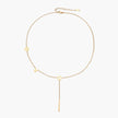 Gold Y-shaped necklace with L-O-V-E letter charms and vertical bar pendant on delicate chain against cream background