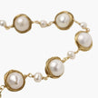 Gold wire-wrapped freshwater pearl bracelet with alternating pearl sizes on cream background, adjustable length