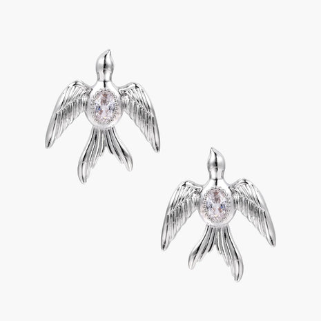 White gold-plated bird earrings with spread wings and oval zirconia center on cream background