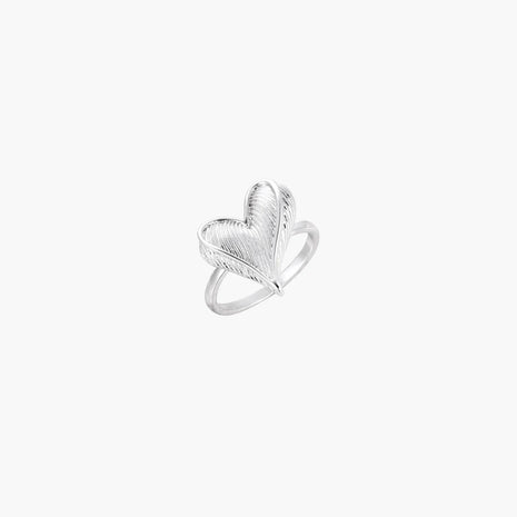 Silver ring with 3D heart formed by textured feather-like elements, white gold plated eco-brass on neutral background.