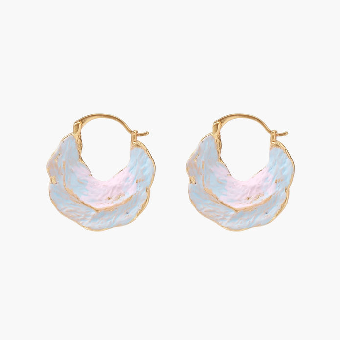 Shell-shaped hoop earrings with iridescent blue-pink enamel and gold trim on cream background