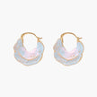 Shell-shaped hoop earrings with iridescent blue-pink enamel and gold trim on cream background