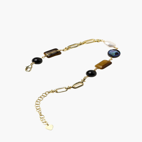 Gold chain bracelet with tiger's eye, obsidian, pearl, and iridescent abalone stones on cream background.
