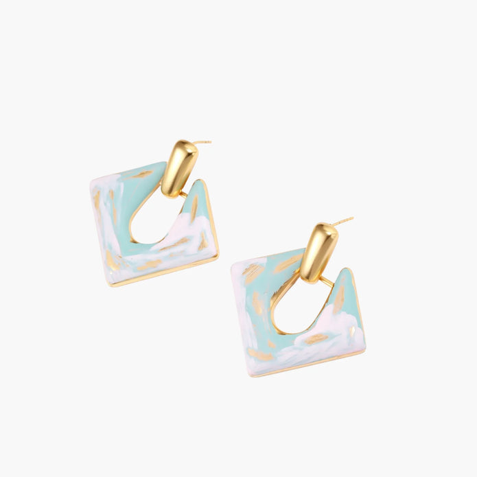 Geometric square enamel earrings with marbled turquoise and lavender pattern, gold U-shaped connector on cream background.