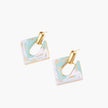 Geometric square enamel earrings with marbled turquoise and lavender pattern, gold U-shaped connector on cream background.