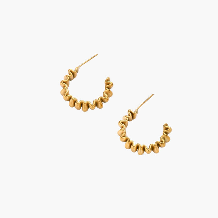 Sculptural gold-plated hoop earrings with continuous twisted spiral design on cream background