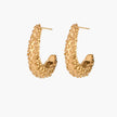 Curved gold hoop earrings with raised granulated texture resembling sea urchin surface on cream background