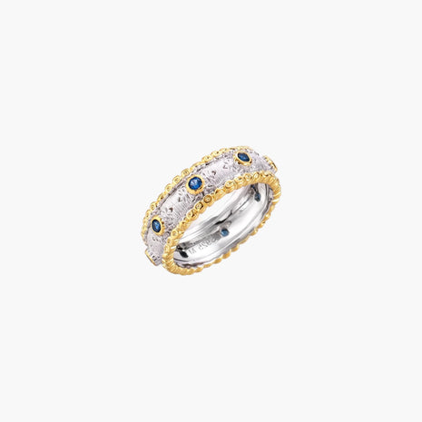 Two-tone ring with brushed silver center, gold beaded edges, and blue zirconia stones on white background.