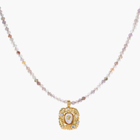 Ornate gold-plated pendant necklace with multicolored gemstone beads in purple, pink and clear tones on white background