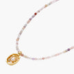 Delicate gold-plated necklace with mixed gemstone beads and ornate oval pendant on white background