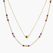 Two layered gold-tone necklaces with purple stone beads and star pendant against cream background.