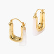 Sculptural gold-plated hoop earrings with flowing curved design and lever-back closure on cream background.