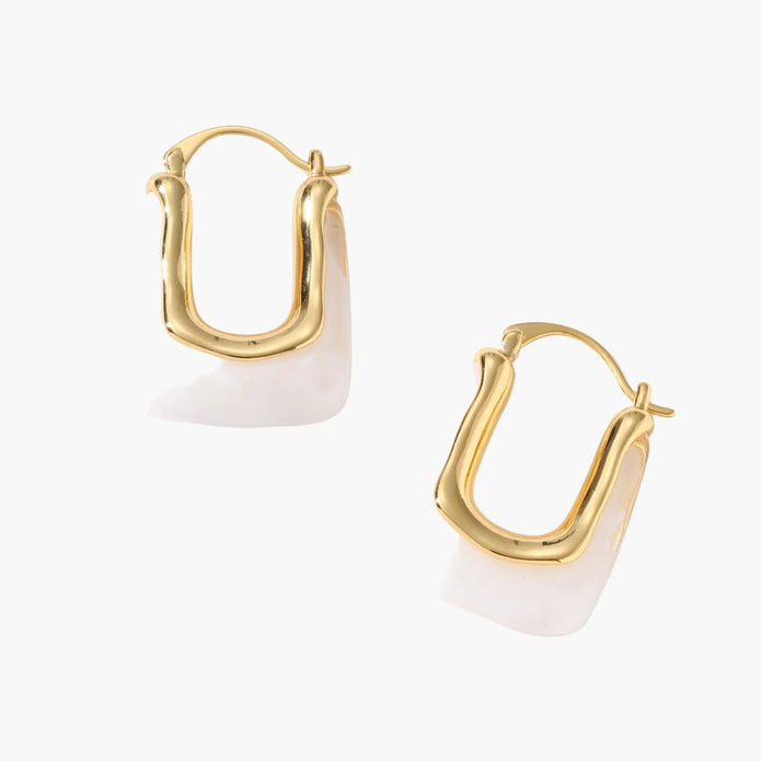 Sculptural gold-plated hoop earrings with flowing curved design and lever-back closure on cream background.