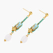 Gold-plated dangle earrings with turquoise threading, star charms, and white pearl beads against cream background.