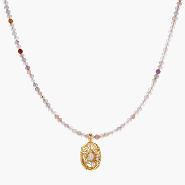Delicate gold-plated necklace with mixed gemstone beads and ornate oval pendant on white background