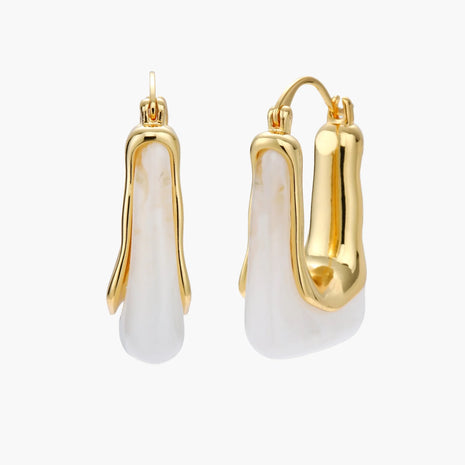 Sculptural gold-plated hoop earrings with flowing curved design and lever-back closure on cream background.