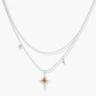 Two-layer silver-toned necklace with star charms and dagger pendant featuring golden sun motif on white background.