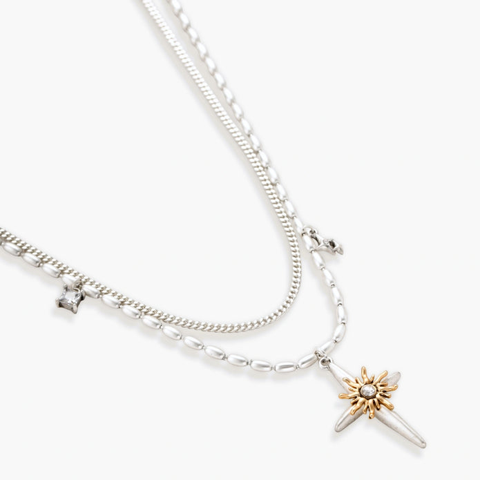 Two-layer silver-toned necklace with star charms and dagger pendant featuring golden sun motif on white background.