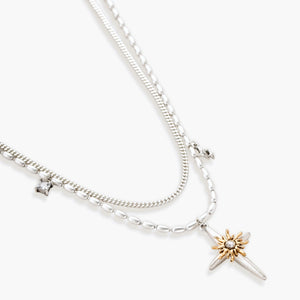 Two-layer silver-toned necklace with star charms and dagger pendant featuring golden sun motif on white background.
