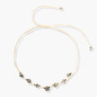 Adjustable cream cord necklace with white spotted stone beads featuring black speckles on neutral background