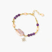 Gold-plated bracelet with baroque pearl centerpiece, amethyst beads, and crystal star charm on white background.