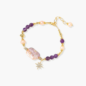 Gold-plated bracelet with baroque pearl centerpiece, amethyst beads, and crystal star charm on white background.