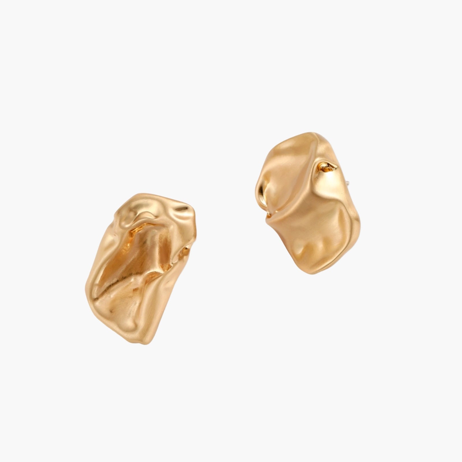 Abstract crumpled metallic earrings with fluid organic shapes in reflective gold and silver finish on neutral background.