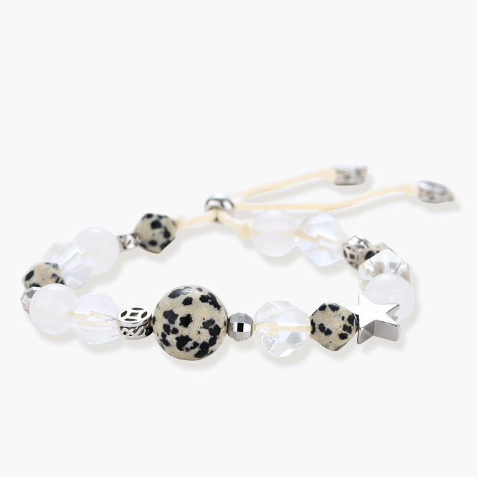 Adjustable beaded bracelet with spotted dalmatian stones, clear quartz crystals, and silver star charm on white background.