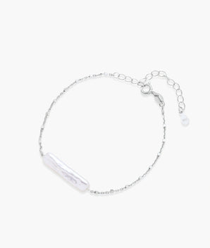 Minimalist bracelet with iridescent baroque pearl on rhodium-plated sterling silver chain against cream background