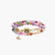 Stretchable bracelet with pastel gemstone beads, freshwater pearls, gold centerpiece and butterfly charm on cream background