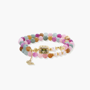 Stretchable bracelet with pastel gemstone beads, freshwater pearls, gold centerpiece and butterfly charm on cream background